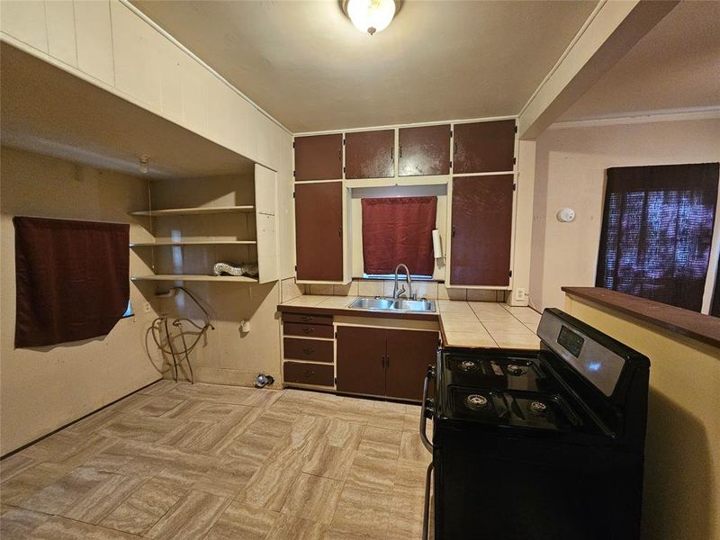 Kitchen featuring black stove, dark brown cabinetry, and sink Kitchen featuring black stove, dark brown cabinetry, and sink