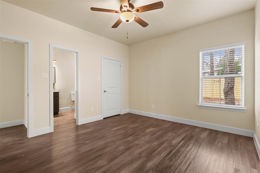 Unfurnished bedroom with dark wood-type flooring, ensuite bath, and ceiling fan