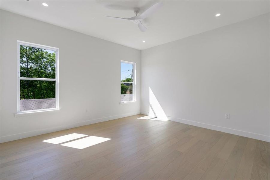 Spare room with a wealth of natural light, light wood-style floors, and baseboards
