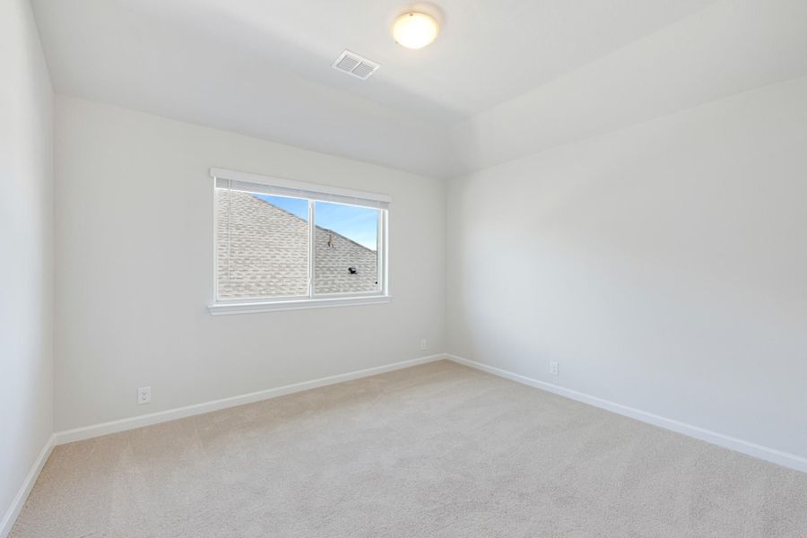 Empty bedroom with white walls, beige carpet, and a single window with exterior view