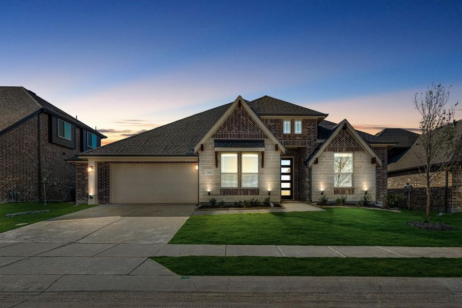 Single-story brick and stone home with two-car garage and green lawn at dusk Single-story brick and stone home with two-car garage and green lawn at dusk