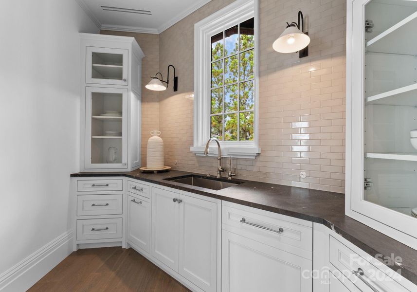 The scullery features custom cabinets, paneled dishwasher, and leathered quartzite.