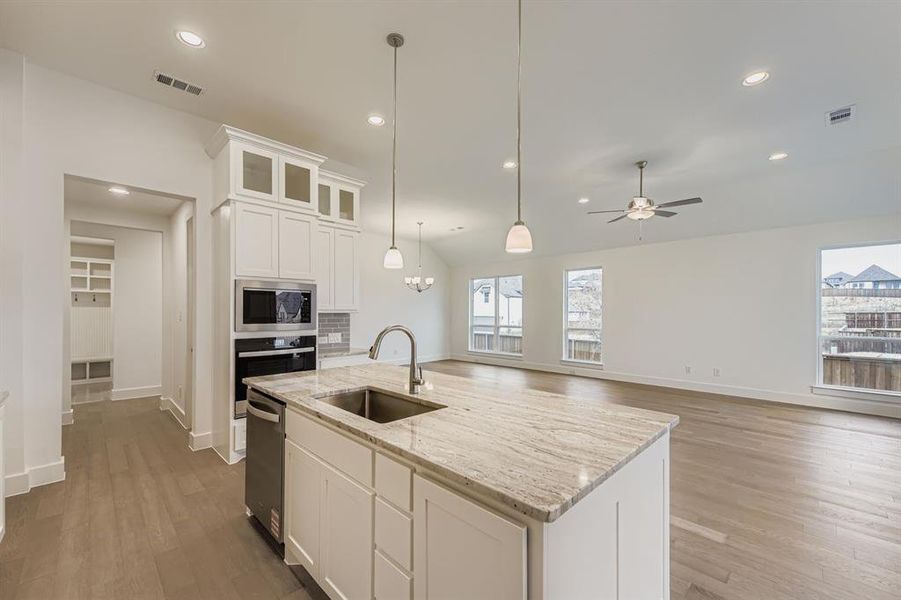 Kitchen with white cabinets, glass insert cabinets, dark wood finished floors, recessed lighting, and hanging light fixtures Kitchen with white cabinets, glass insert cabinets, dark wood finished floors, recessed lighting, and hanging light fixtures