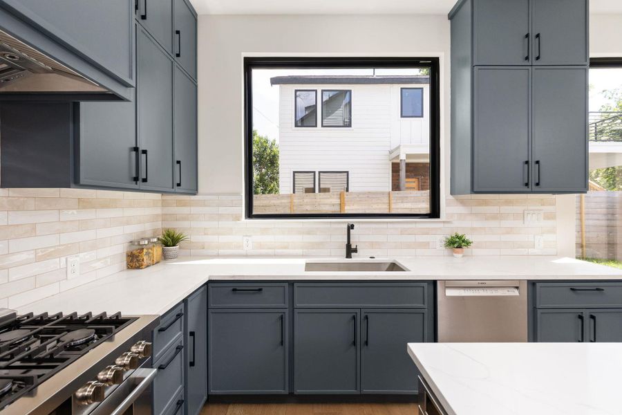 Culinary adventures await in this kitchen with expansive counters, modern cabinetry, and abundant natural light.