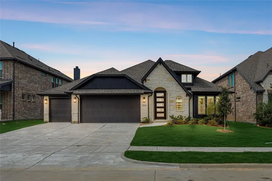 Single-story home with stone and brick exterior, three-car garage, arched entry, and landscaped front yard