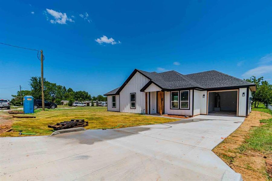 Modern farmhouse style home with roof with shingles, a front lawn, driveway, and a garage Modern farmhouse style home with roof with shingles, a front lawn, driveway, and a garage