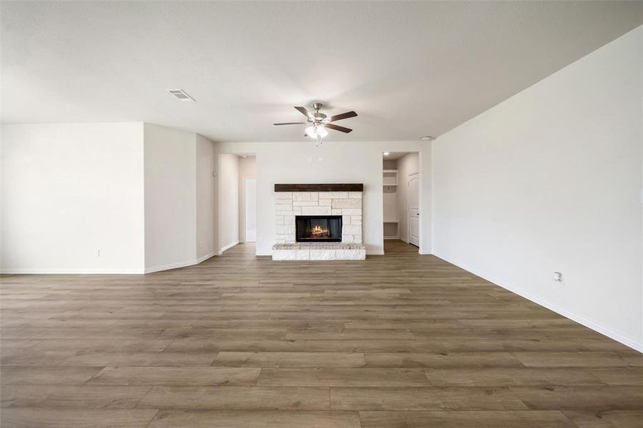 Unfurnished living room with wood finished floors, a fireplace, and a ceiling fan