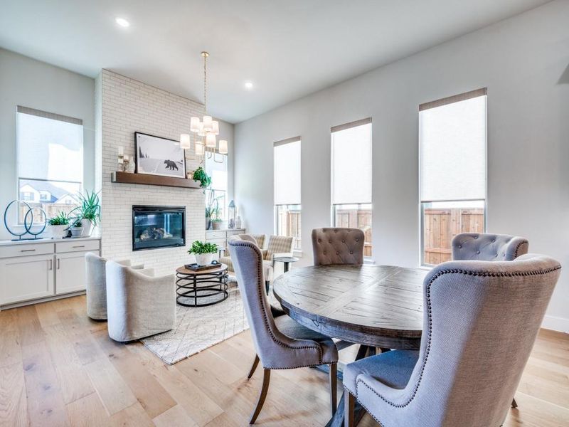 Dining area featuring a chandelier, light wood-type flooring, recessed lighting, and a brick fireplace