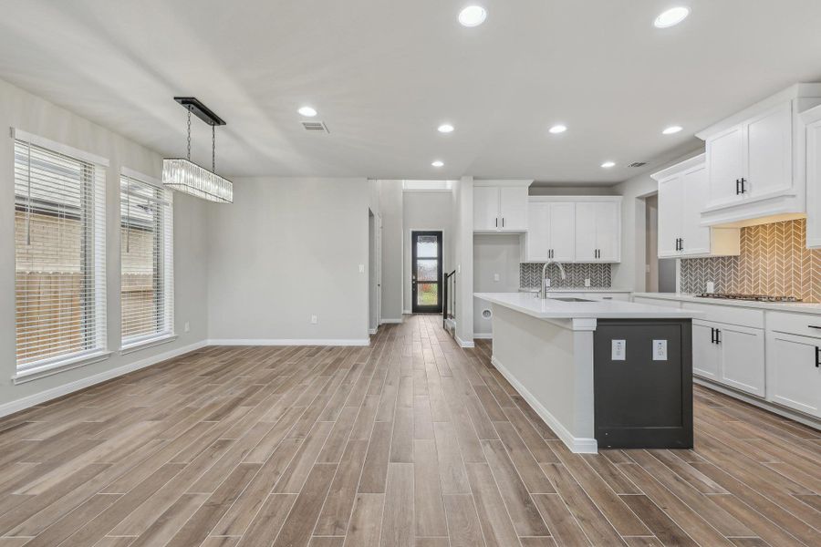 Kitchen with stainless steel gas cooktop, a sink, light wood-style floors, light countertops, and recessed lighting Kitchen with stainless steel gas cooktop, a sink, light wood-style floors, light countertops, and recessed lighting