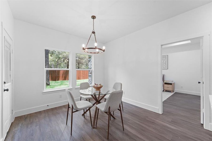 Spacious interior room with wood-finish flooring, white baseboards, and white walls Spacious interior room with wood-finish flooring, white baseboards, and white walls