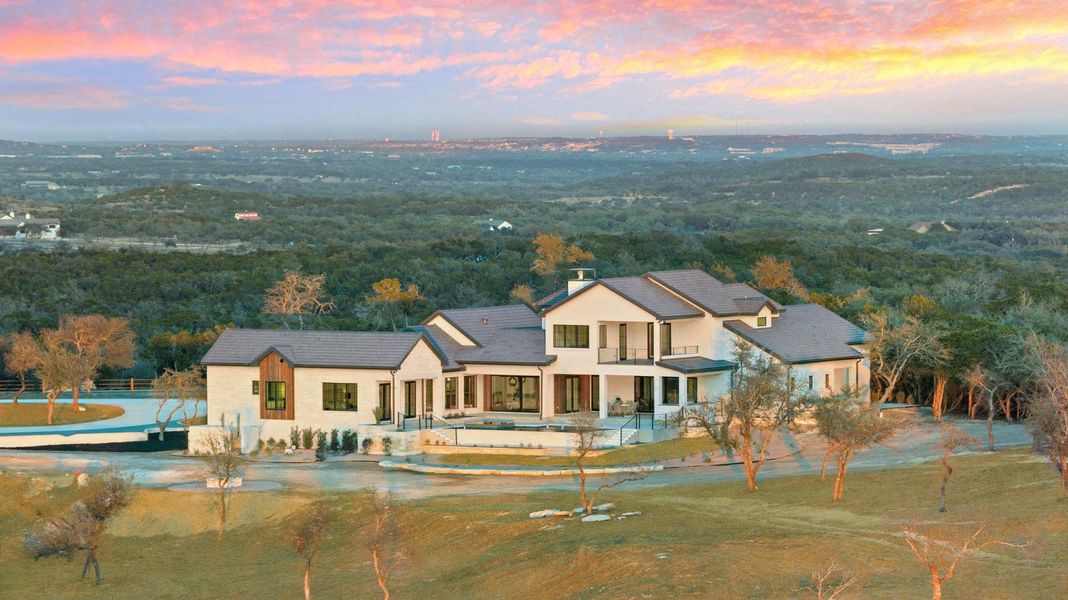 Aerial view at dusk of back of home with pool and outdoor living.