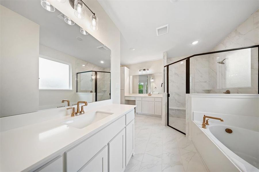 Bathroom featuring two vanities, a marble finish shower, light marble finish floors, and a bath