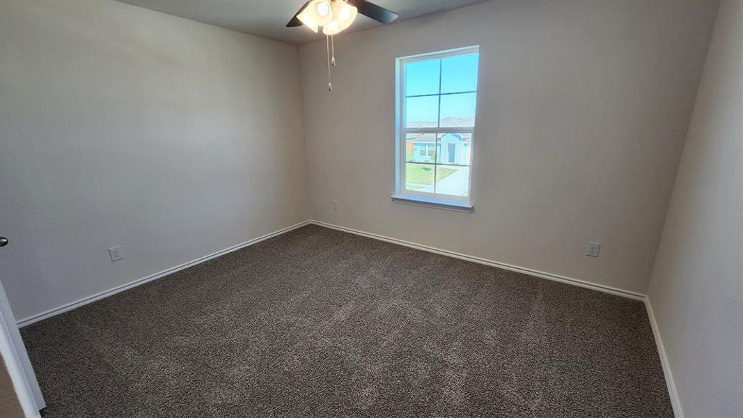 Bedroom featuring textured carpeting, neutral wall paint, and a multi-pane window Bedroom featuring textured carpeting, neutral wall paint, and a multi-pane window