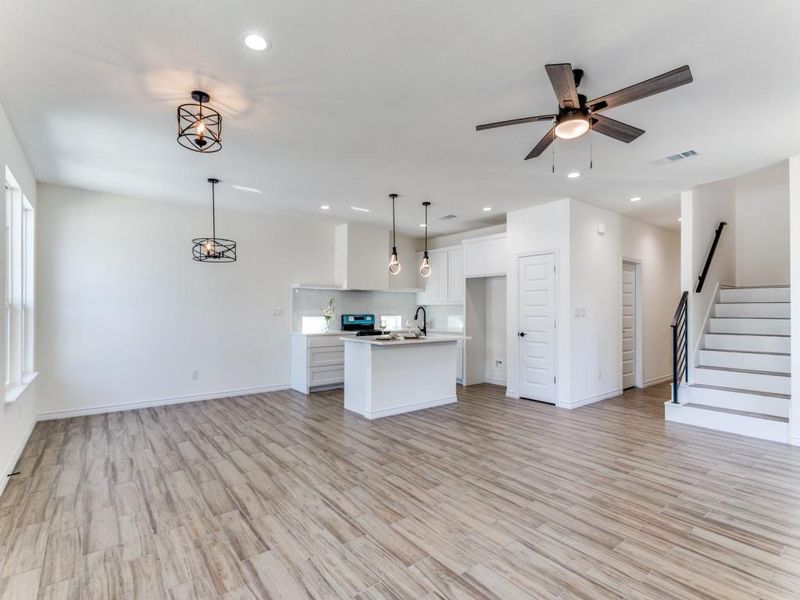 Kitchen featuring an island with sink, light hardwood / wood-style flooring, decorative light fixtures, and white cabinets