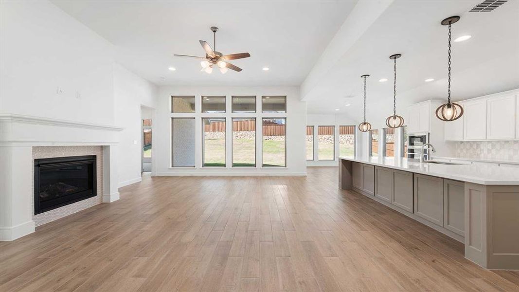 Unfurnished living room with sink, light hardwood / wood-style flooring, ceiling fan, and plenty of natural light