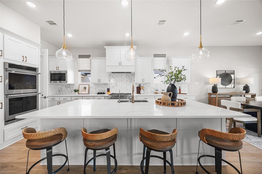 Open-concept kitchen designed for entertaining, featuring a spacious center island, breakfast bar seating, abundant counter space, and a seamless flow into the living and dining areas—perfect for hosting family and friends.