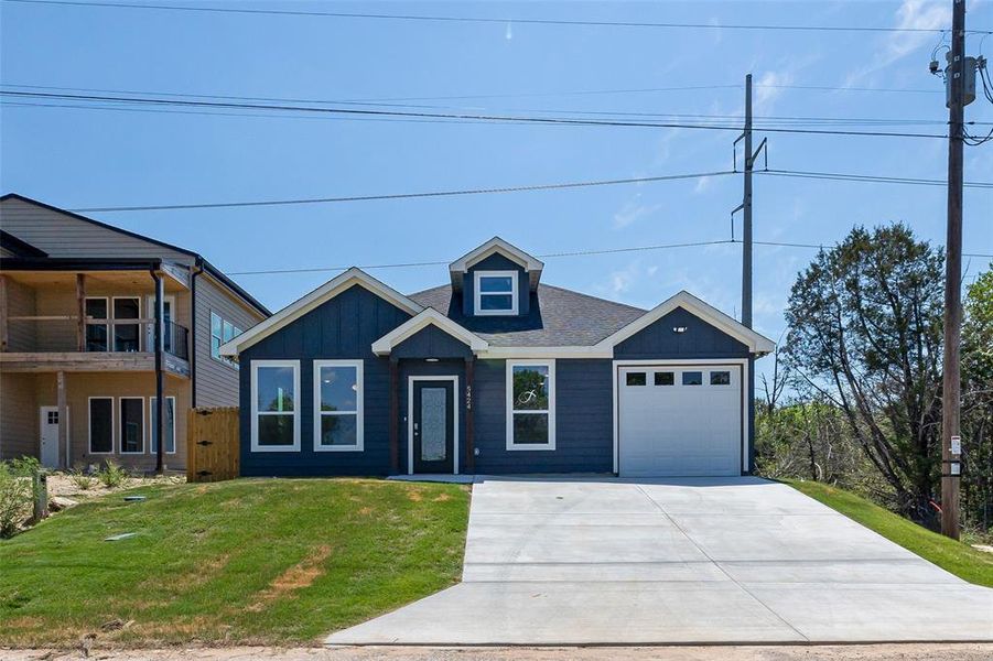 View of front of home featuring a garage, a balcony, and a front yard