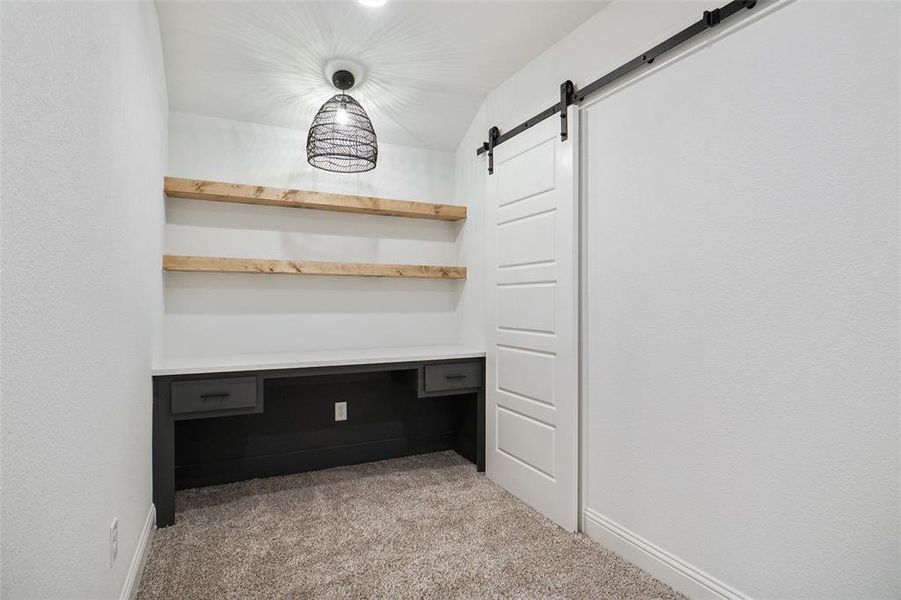 Unfurnished office with light colored carpet and a barn door