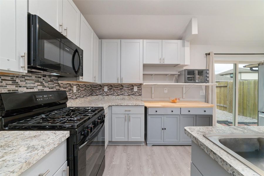 Bright kitchen with ample cabinetry and natural light, offering a functional layout that flows easily to the dining area and outdoor access.