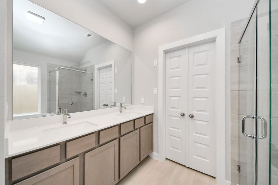 Enhance your daily routine at the refined vanity area, which boasts dual sinks, sleek countertops in soft, light tones, and modern fixtures. The bright, stylish lighting adds a touch of sophistication, creating a luxurious atmosphere that complements the entire space. Sample photo of completed home with similar floor plan. Actual colors and selections may vary.