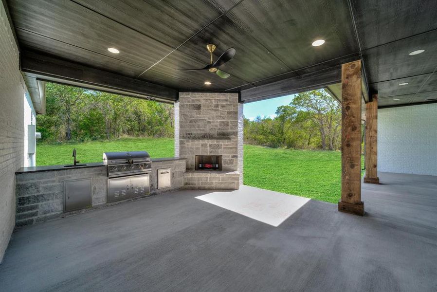 View of patio / terrace featuring an outdoor stone fireplace, exterior kitchen, and ceiling fan