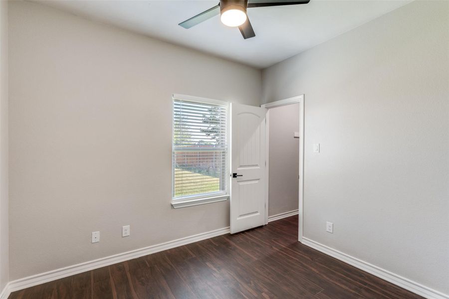 Unfurnished room featuring dark wood-style flooring and a ceiling fan Unfurnished room featuring dark wood-style flooring and a ceiling fan