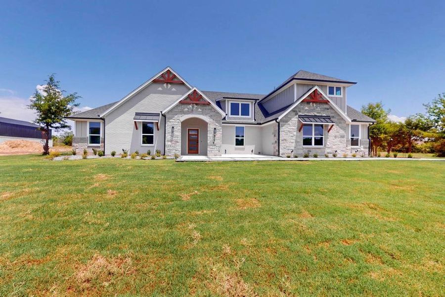 View of front facade with stone siding, a front yard, and board and batten siding