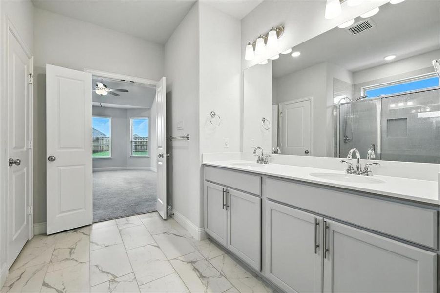 Large primary bath with walk in closet, built in cabinets, dual sinks, linen and natural light