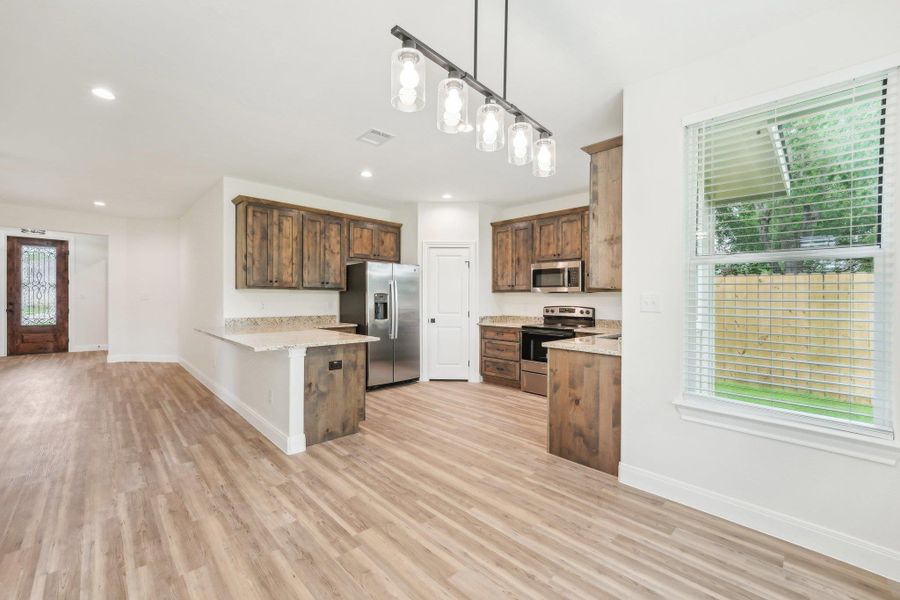 Kitchen with a peninsula, plenty of natural light, visible vents, and appliances with stainless steel finishes Kitchen with a peninsula, plenty of natural light, visible vents, and appliances with stainless steel finishes