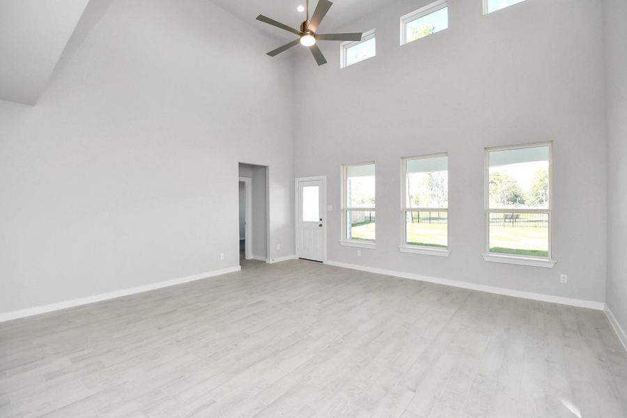 Bring your loved ones and guests together in the inviting living room! Boasting lofty high ceilings, recessed lighting, a stylish ceiling fan, custom paint, stunning flooring, and expansive windows that flood the space with ample natural light all day long. Sample photo of completed home with similar floor plan. Actual colors and selections may vary.
