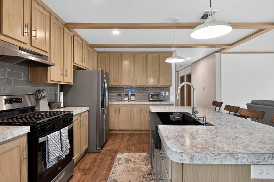 An inviting kitchen with stainless steel appliances, a generous island, and rich wood cabinetry awaits culinary adventures.