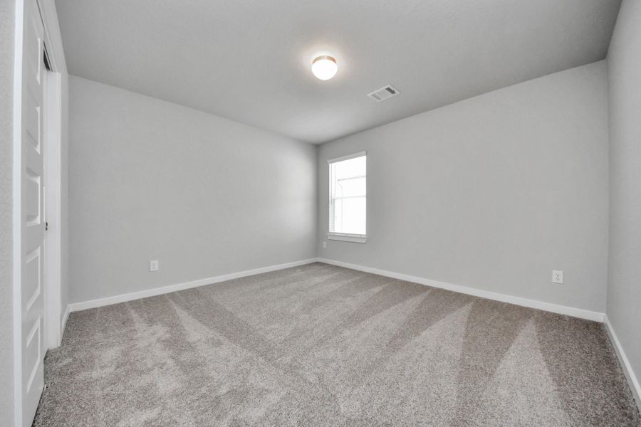 Secondary bedroom features plush carpeting, large windows that let in plenty of natural light, bright paint, and spacious closets. Sample photo of completed home with similar floor plan. Actual colors and selections may vary.