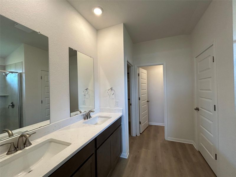 Full bathroom featuring dark wood-style flooring, double vanity, and a stall shower Full bathroom featuring dark wood-style flooring, double vanity, and a stall shower