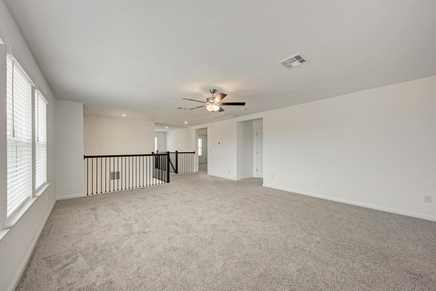 A spacious upper-level living area features soft carpeting and abundant natural light.