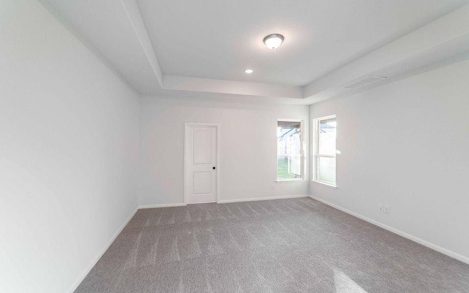 Carpeted empty room featuring a tray ceiling and recessed lighting