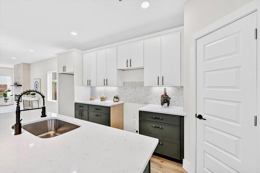 Contemporary kitchen featuring white upper cabinetry, contrasting dark lower cabinetry, and light quartz countertops