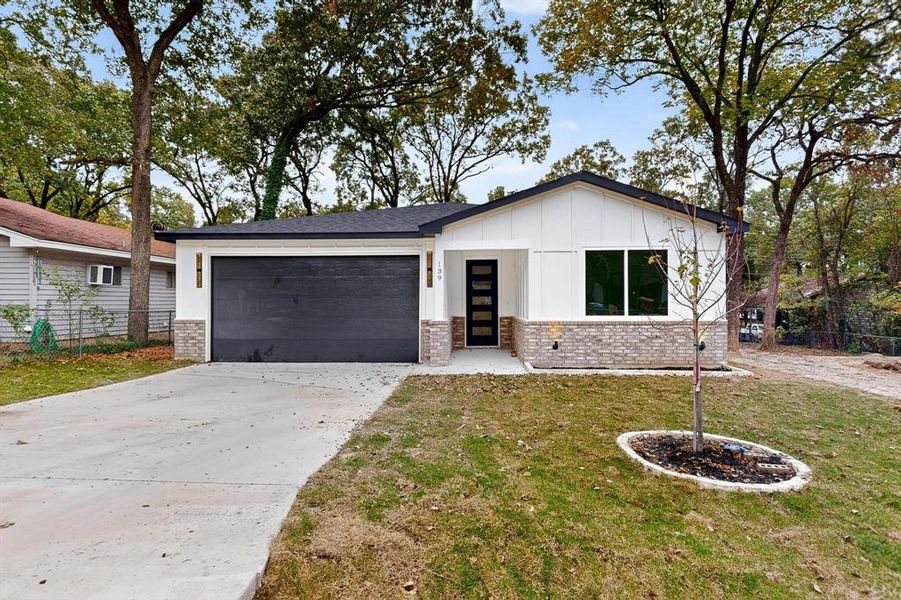 View of front of house with board and batten siding, brick siding, concrete driveway, and a garage View of front of house with board and batten siding, brick siding, concrete driveway, and a garage