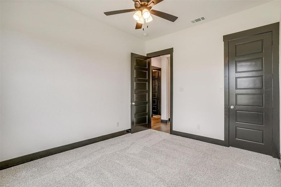 Unfurnished bedroom with ceiling fan and dark carpet