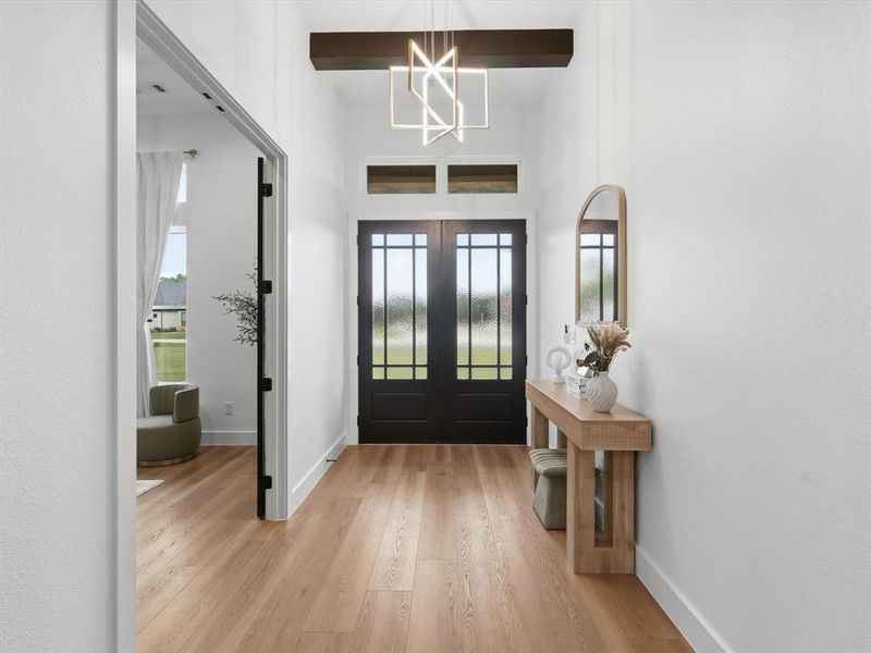 Entryway featuring wood-finish flooring, white walls, and a high ceiling