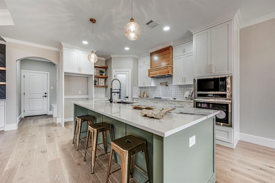 Kitchen with white cabinetry, sink, a breakfast bar area, a kitchen island with sink, and black appliances