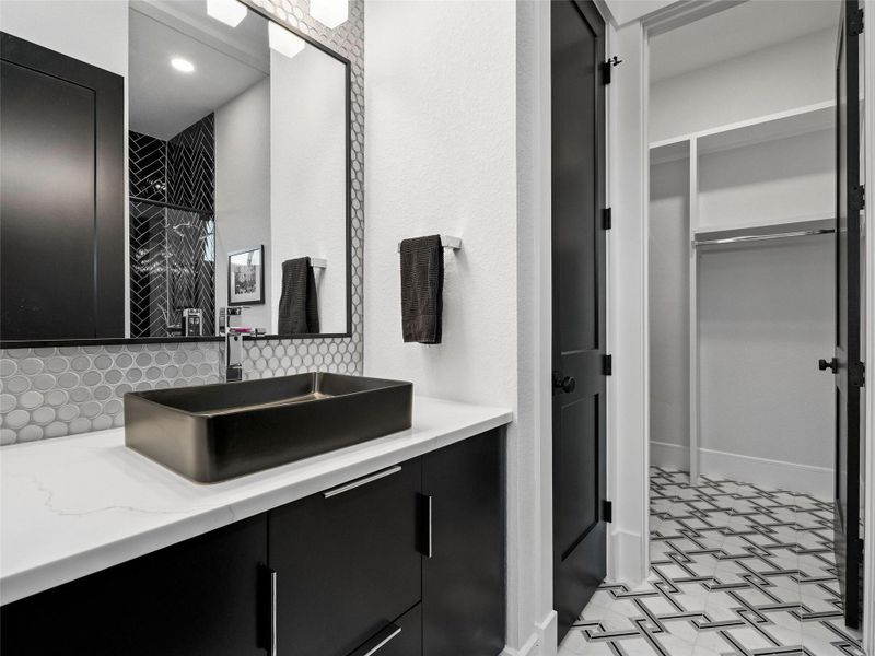 Bathroom with backsplash, vanity, a walk in closet, and a shower