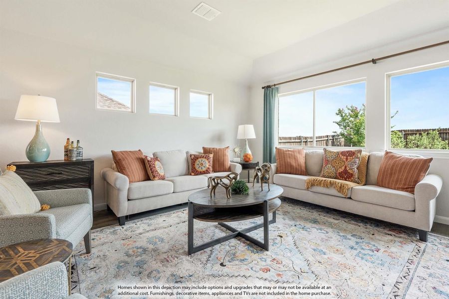 Living room with two beige sofas, round coffee table, patterned area rug, and large windows with natural light Living room with two beige sofas, round coffee table, patterned area rug, and large windows with natural light