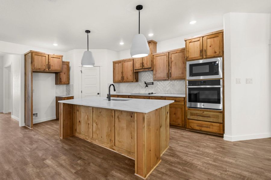 Culinary delights await in this newly-appointed kitchen, featuring a spacious island with sink and stainless steel appliances.