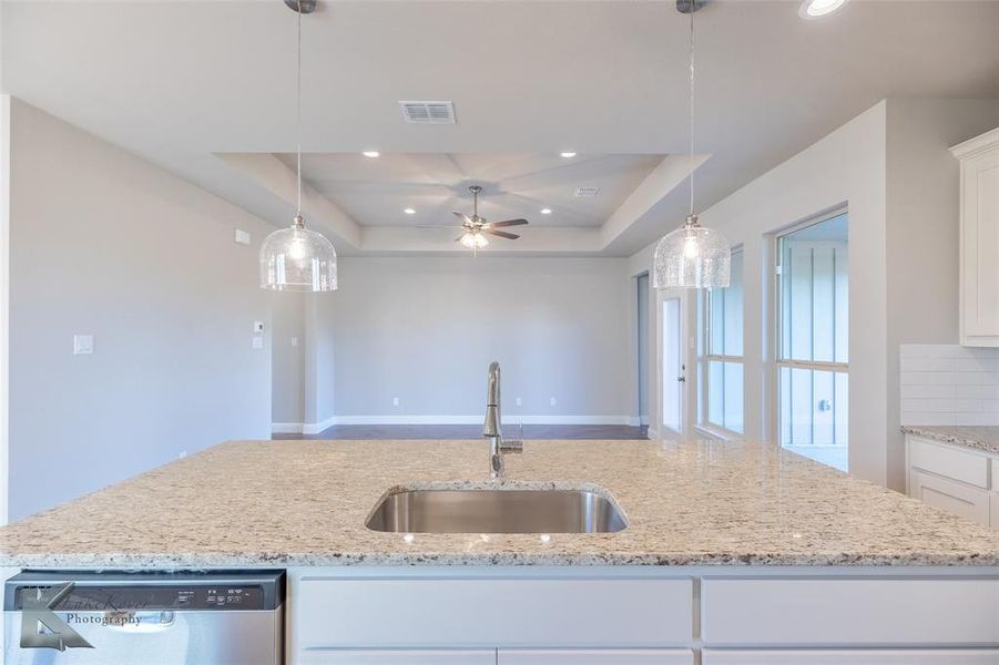 Kitchen featuring white cabinetry, light stone countertops, stainless steel dishwasher, hanging light fixtures, and recessed lighting