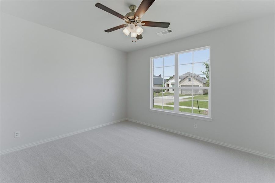 Carpeted interior space featuring a multi-pane window with white trim, a ceiling fan with integrated lighting, and neutral wall tones