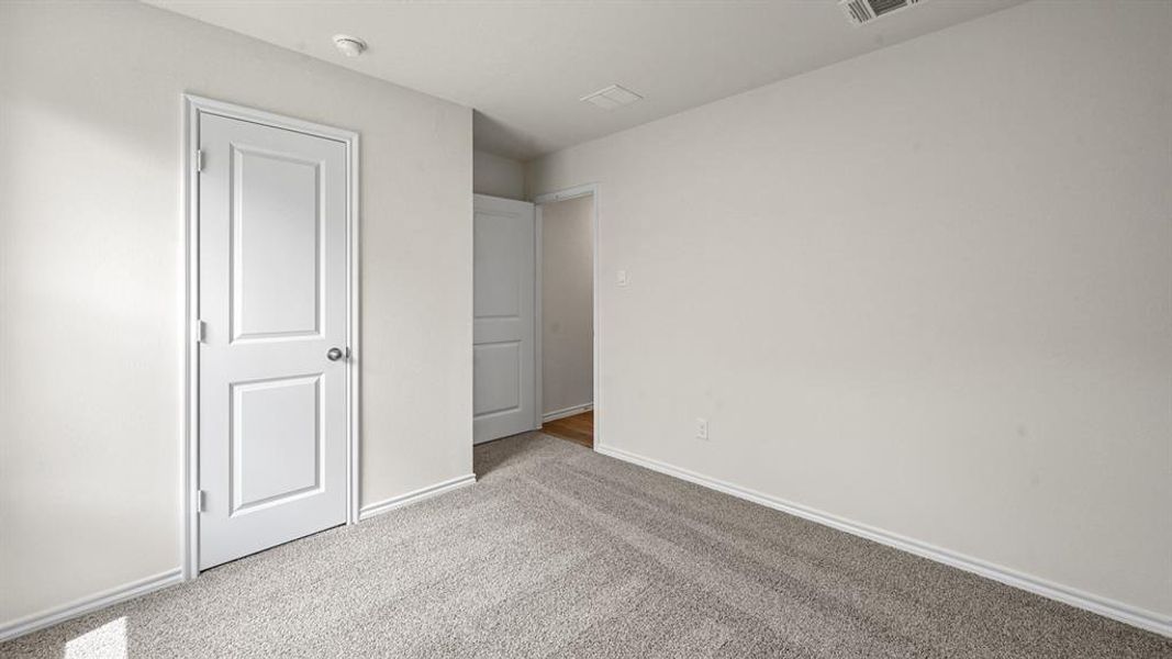 Unfurnished bedroom with light carpet and baseboards