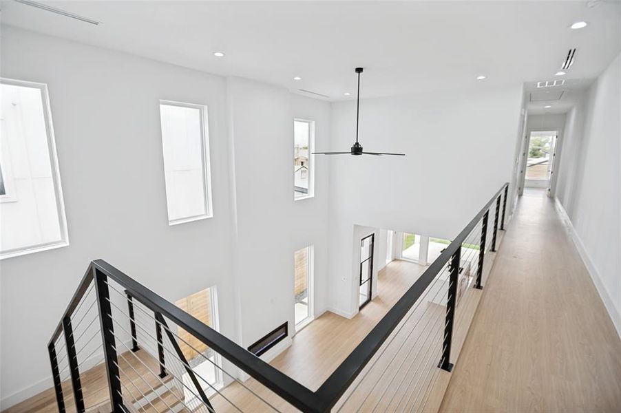 Open-concept interior featuring high ceilings, contemporary light wood-finish flooring, and minimalist white walls