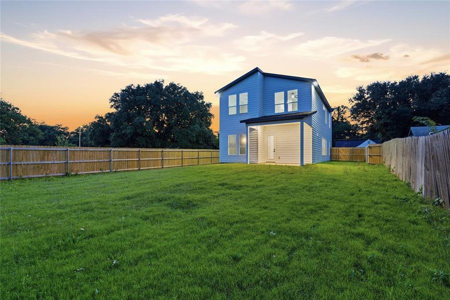 Expansive backyard featuring a large green lawn, full perimeter privacy fencing, and a covered patio area Expansive backyard featuring a large green lawn, full perimeter privacy fencing, and a covered patio area