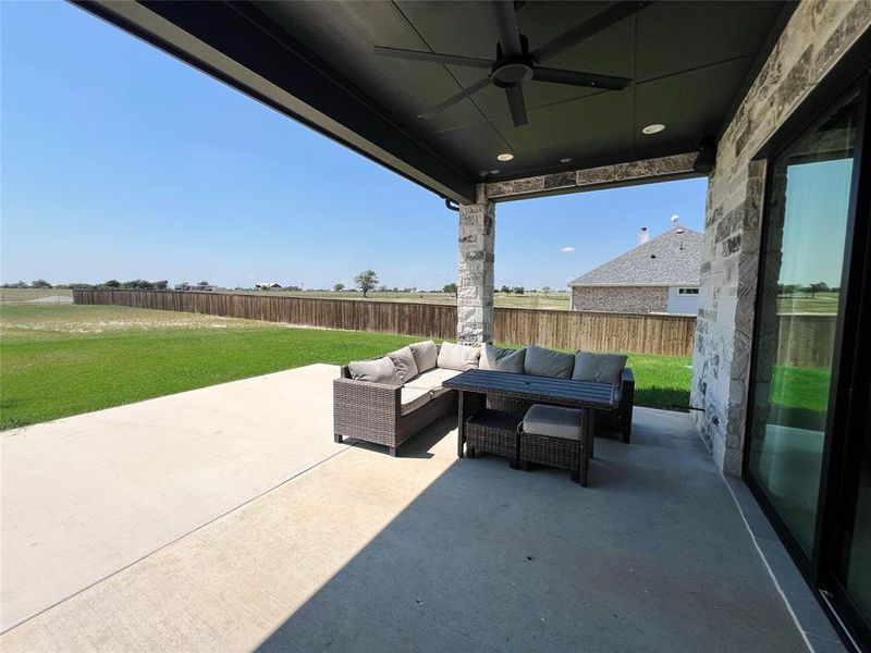 Fenced backyard with a ceiling fan, an outdoor hangout area, and a patio area
