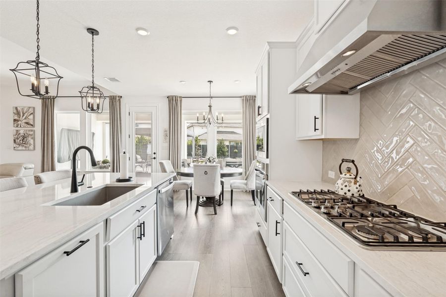 Crisp white cabinetry paired with sleek stone countertops defines this open-concept culinary space.